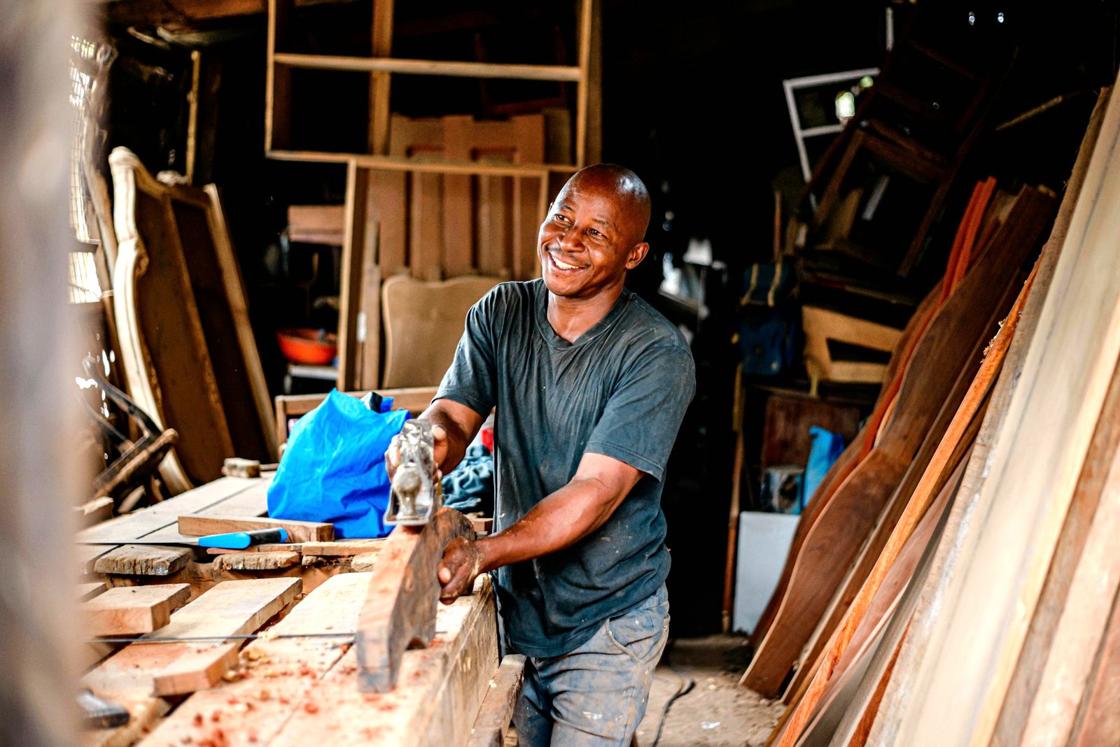 Carpenter smiling while planing timber in a workshop