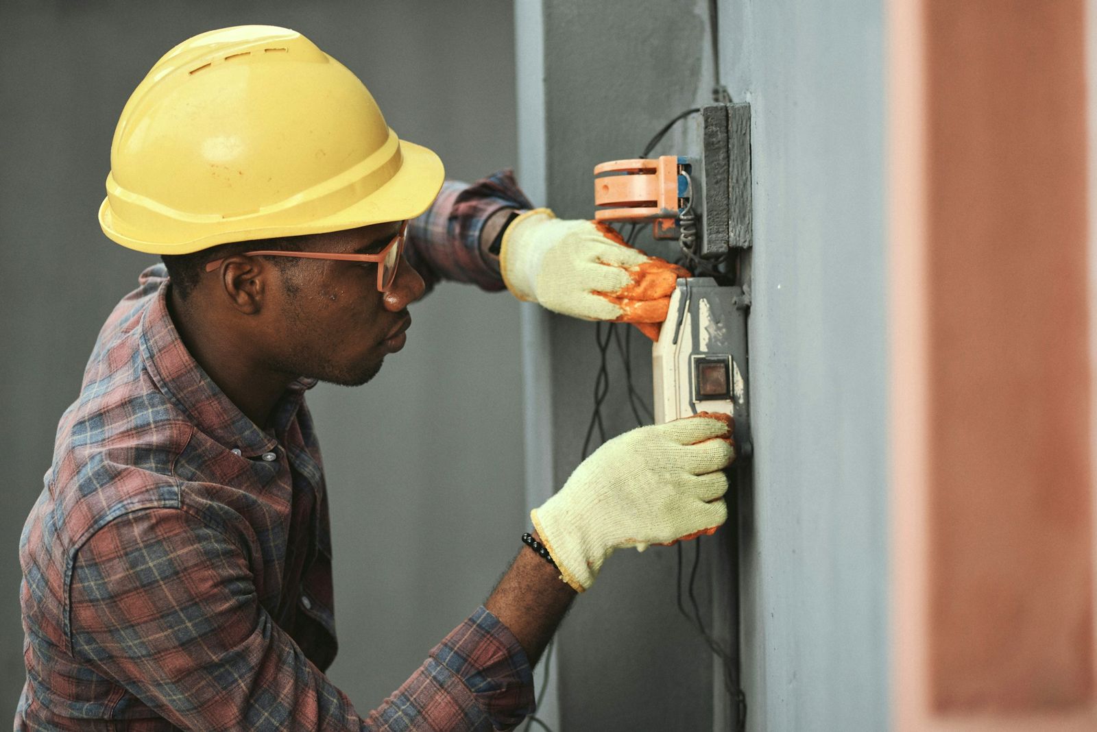 Electrician in a hard hat working on an outdoor electrical box
