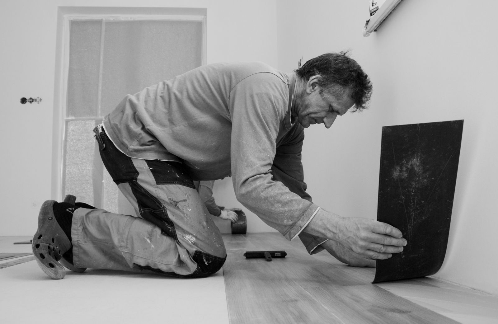 Flooring installer fitting a plank on a new floor