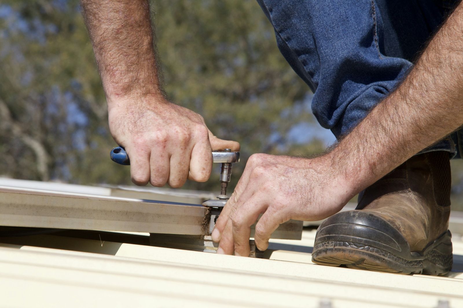 Hands fastening metal roofing with a ratchet